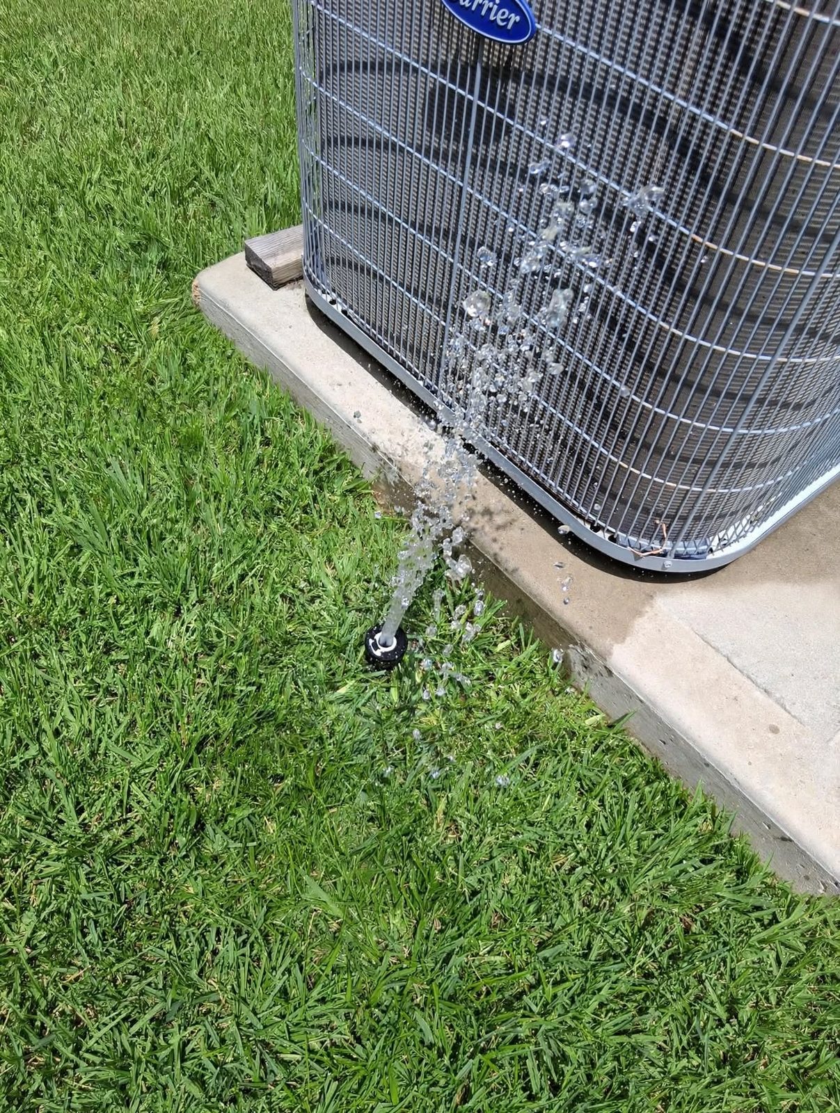 Sprinkler head spraying directly onto an outdoor AC condenser unit